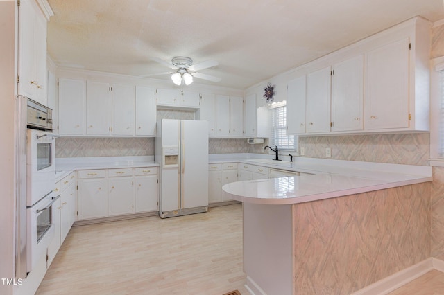 kitchen with a sink, a peninsula, light countertops, and white fridge with ice dispenser