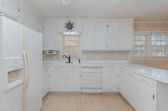 kitchen featuring a sink, white appliances, a wealth of natural light, and light countertops