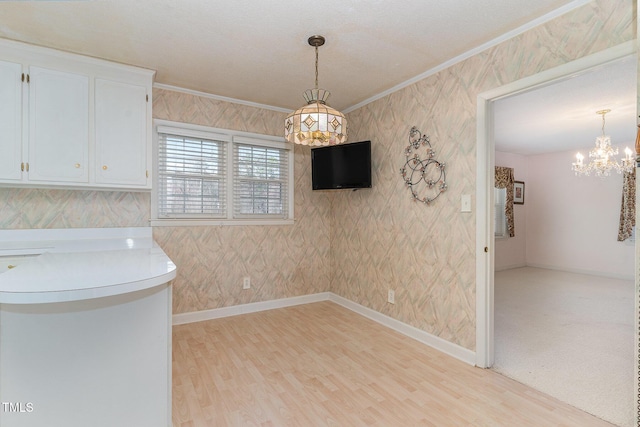 unfurnished dining area with baseboards, crown molding, and light wood finished floors