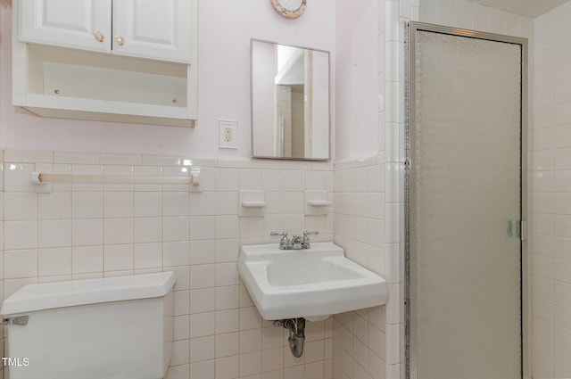 bathroom featuring toilet, a sink, tile walls, wainscoting, and a shower stall