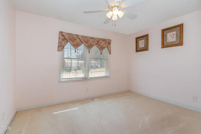 carpeted spare room featuring visible vents, baseboards, and a ceiling fan