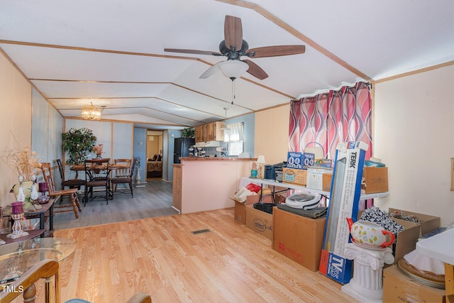 kitchen with ceiling fan with notable chandelier, wood finished floors, freestanding refrigerator, a peninsula, and vaulted ceiling