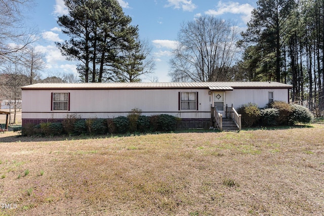 manufactured / mobile home featuring metal roof and a front lawn