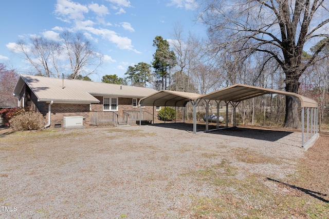 exterior space with brick siding, a detached carport, and driveway