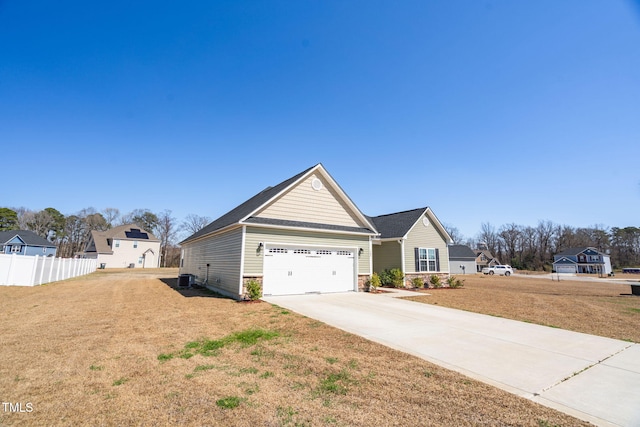 view of front facade with concrete driveway, an attached garage, fence, and a front yard