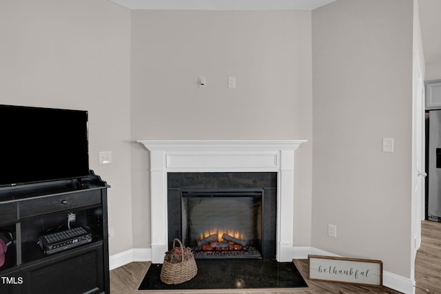 details with stainless steel fridge, a tile fireplace, baseboards, and wood finished floors