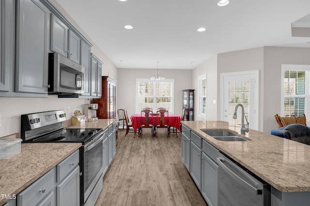 kitchen with light wood finished floors, recessed lighting, gray cabinets, a sink, and stainless steel appliances