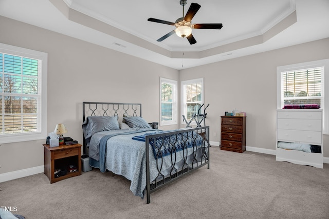 carpeted bedroom featuring visible vents, crown molding, baseboards, a tray ceiling, and a ceiling fan