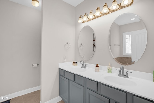 full bath featuring tile patterned floors, double vanity, baseboards, and a sink