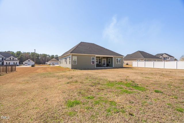 back of house with fence and a lawn