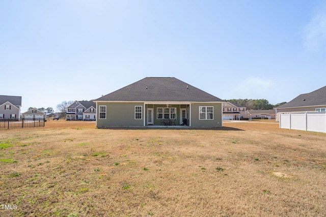 rear view of property featuring a yard and fence