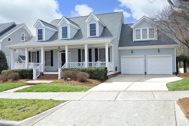 cape cod-style house featuring an attached garage, a porch, concrete driveway, and roof with shingles