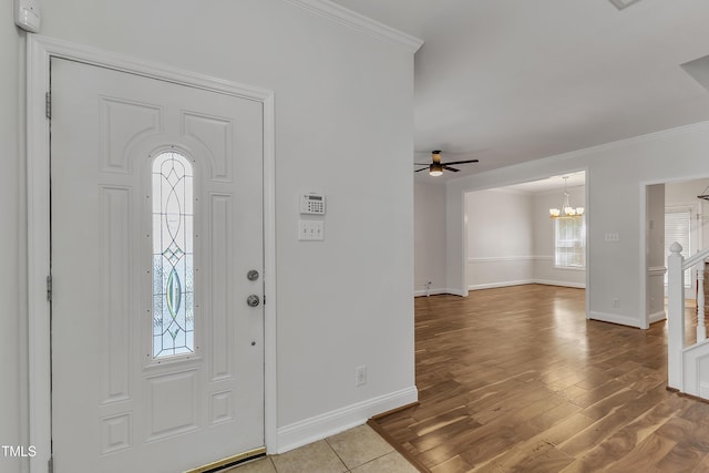 foyer entrance with baseboards, wood finished floors, ornamental molding, and ceiling fan with notable chandelier