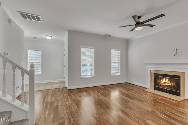 unfurnished living room featuring stairs, plenty of natural light, wood finished floors, and visible vents