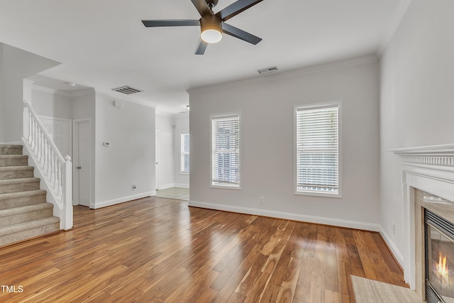 unfurnished living room with visible vents, wood finished floors, a fireplace, and crown molding