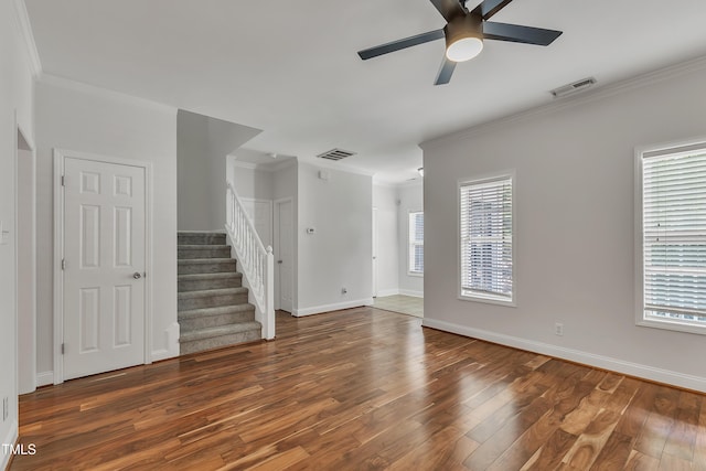 unfurnished living room featuring visible vents, stairway, wood finished floors, and ornamental molding