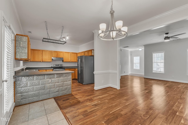 kitchen featuring dark countertops, crown molding, under cabinet range hood, and stainless steel appliances