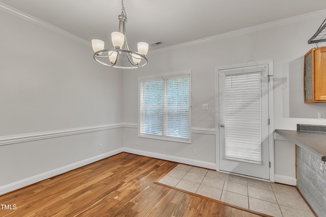 unfurnished dining area with visible vents, an inviting chandelier, light wood-style floors, and ornamental molding