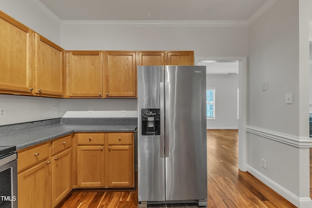 kitchen featuring stainless steel fridge, dark wood-type flooring, dark countertops, and ornamental molding