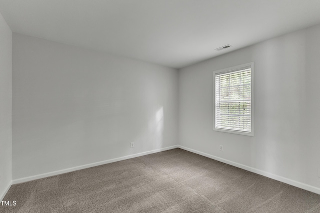 unfurnished room featuring baseboards, visible vents, and dark carpet