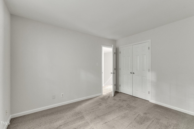 unfurnished bedroom with baseboards, carpet floors, and a closet