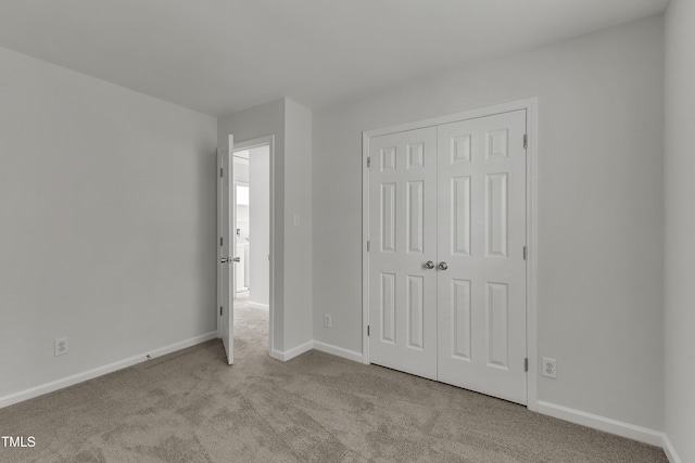 unfurnished bedroom featuring a closet, baseboards, and carpet