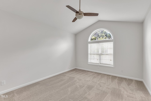 spare room with vaulted ceiling, a ceiling fan, baseboards, and light carpet