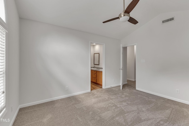 unfurnished bedroom with light carpet, visible vents, baseboards, and vaulted ceiling