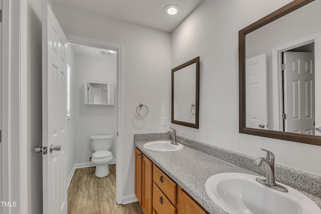 full bathroom with double vanity, wood finished floors, toilet, and a sink