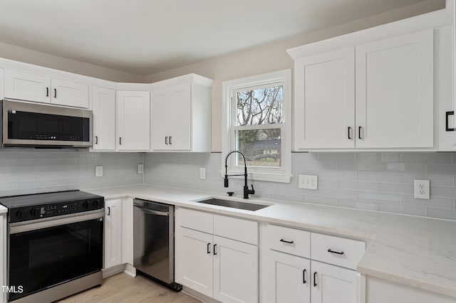 kitchen with a sink, stainless steel appliances, and white cabinets