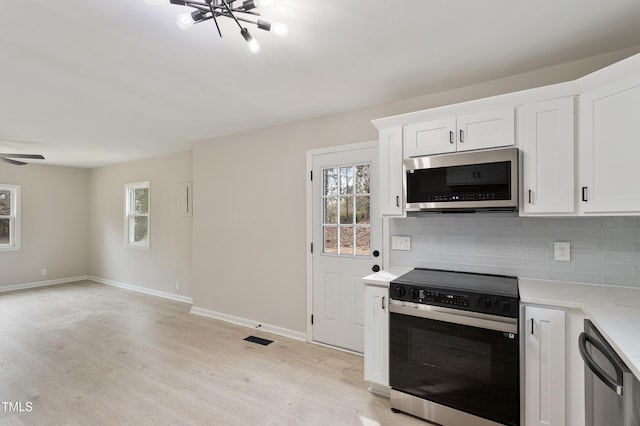 kitchen featuring tasteful backsplash, white cabinets, appliances with stainless steel finishes, and light wood-type flooring