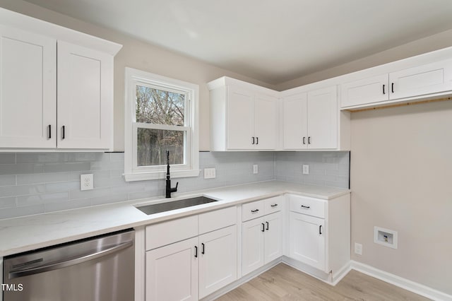 kitchen with light wood finished floors, backsplash, dishwasher, white cabinets, and a sink