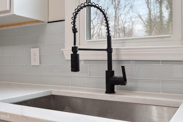 details with decorative backsplash, light stone countertops, and a sink