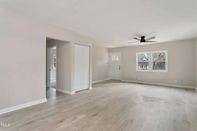 spare room featuring light wood-style flooring, a ceiling fan, and baseboards