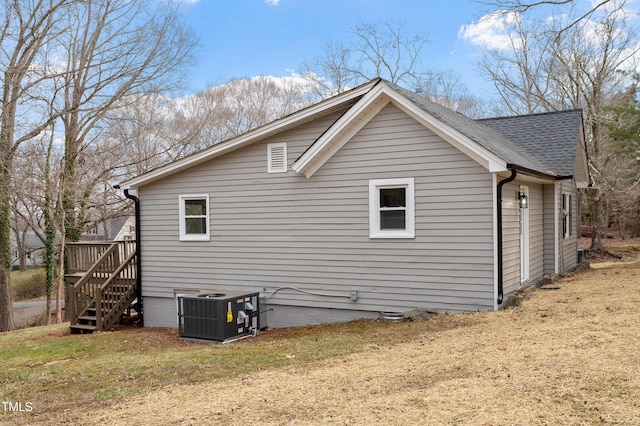 view of side of home with a lawn, central AC, stairs, and a shingled roof