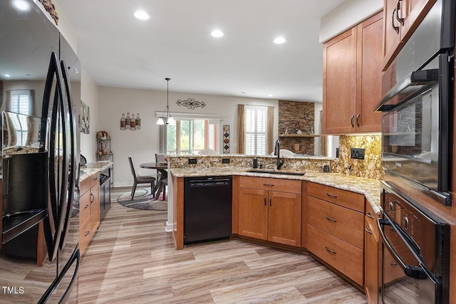 kitchen with backsplash, brown cabinets, a peninsula, black appliances, and a sink