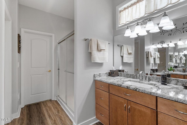 bathroom featuring a shower stall, vanity, baseboards, and wood finished floors