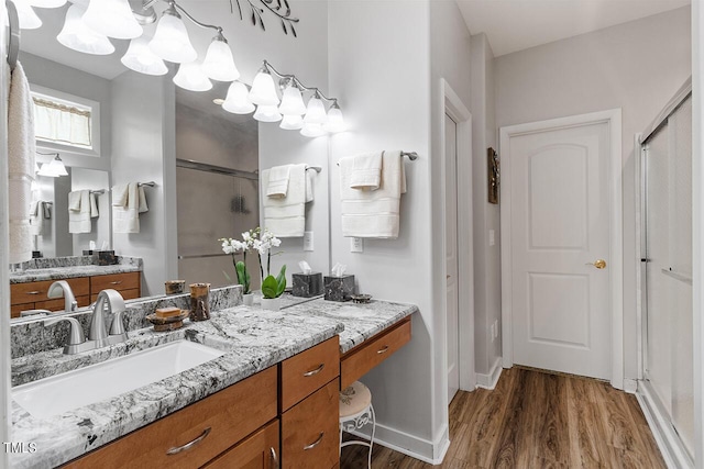 full bath featuring vanity, a shower stall, wood finished floors, and baseboards