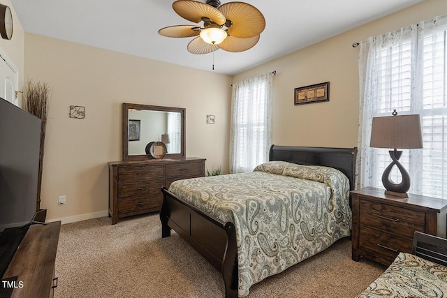 bedroom with a ceiling fan, baseboards, and light carpet