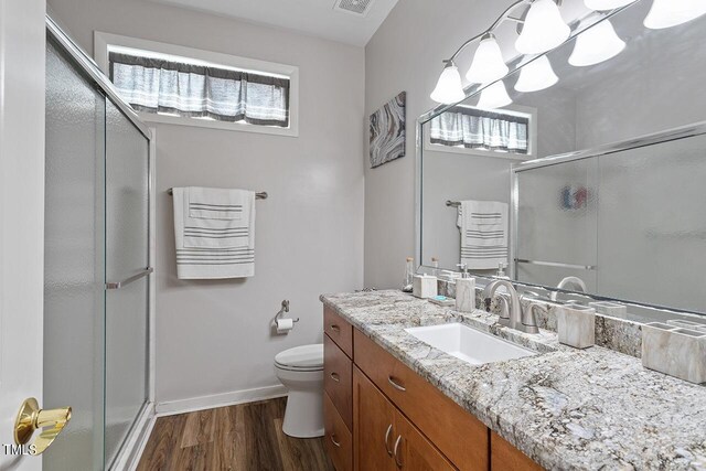 full bath featuring toilet, a stall shower, an inviting chandelier, wood finished floors, and vanity