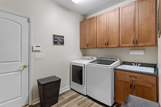 laundry area with light wood-style flooring, a sink, cabinet space, separate washer and dryer, and baseboards