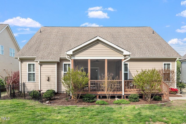 back of property with a lawn, a shingled roof, a sunroom, and fence