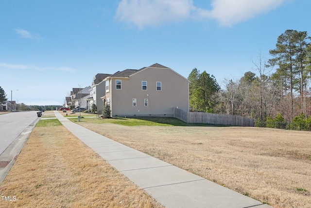 view of home's exterior featuring a residential view, a lawn, and fence