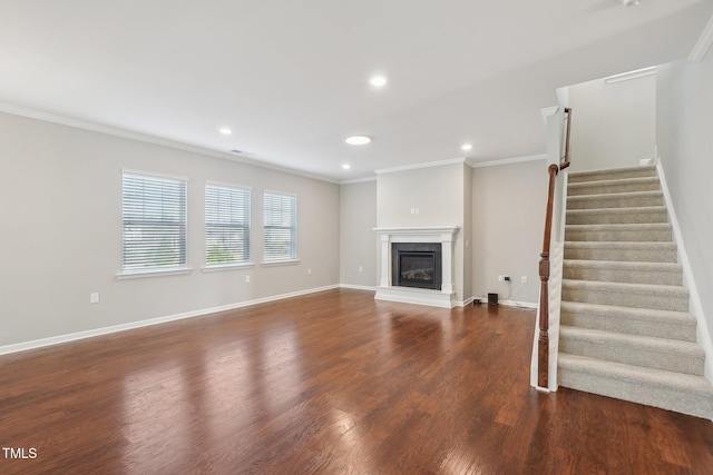 unfurnished living room with a glass covered fireplace, crown molding, wood finished floors, and baseboards