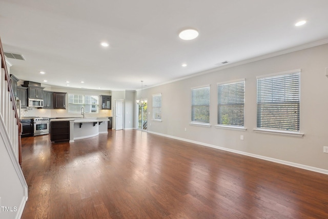 unfurnished living room featuring visible vents, dark wood-type flooring, a sink, crown molding, and baseboards