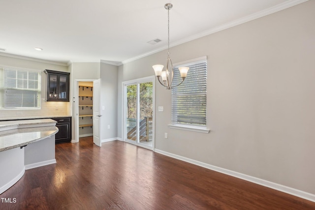 unfurnished dining area featuring visible vents, baseboards, ornamental molding, an inviting chandelier, and dark wood-style floors