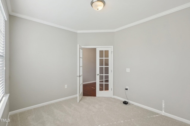 empty room with french doors, carpet floors, baseboards, and crown molding