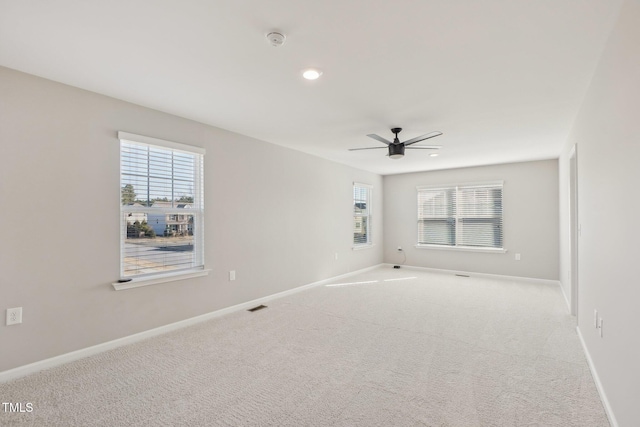 spare room featuring baseboards, visible vents, a wealth of natural light, and light carpet