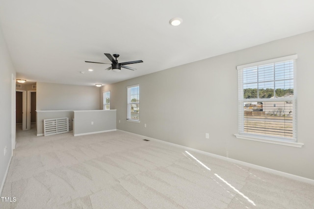 carpeted empty room with visible vents, a healthy amount of sunlight, and baseboards