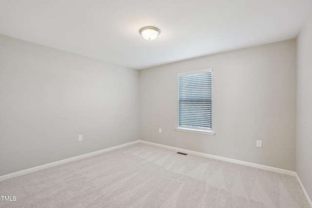 unfurnished room with visible vents, light colored carpet, and baseboards